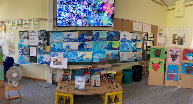Kinderzimmer mit Wellenbildern, Spielzeug und kreativen Bastelarbeiten an der Wand.