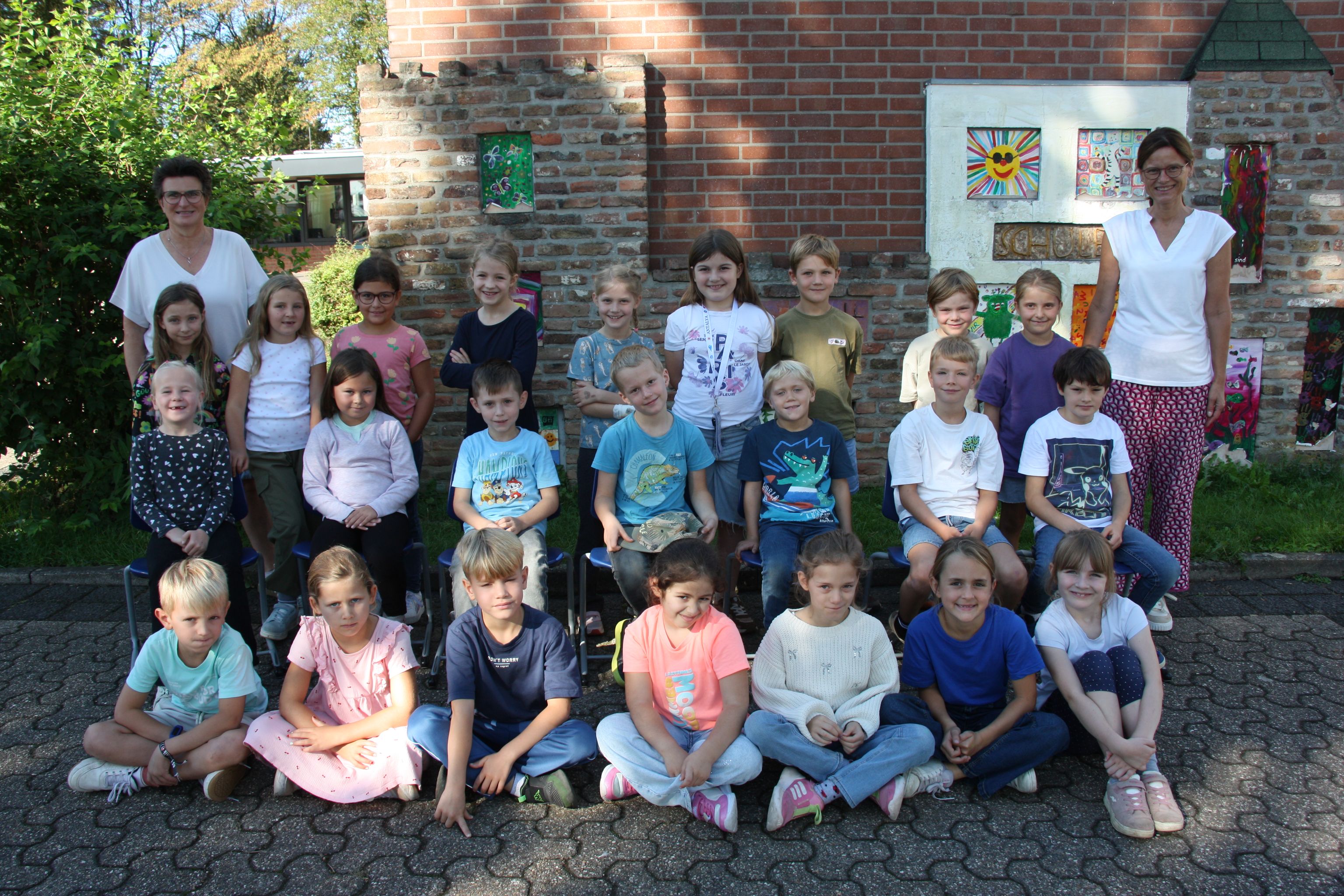 Großgruppe von Kindern und Betreuern vor einem Haus im Freien.