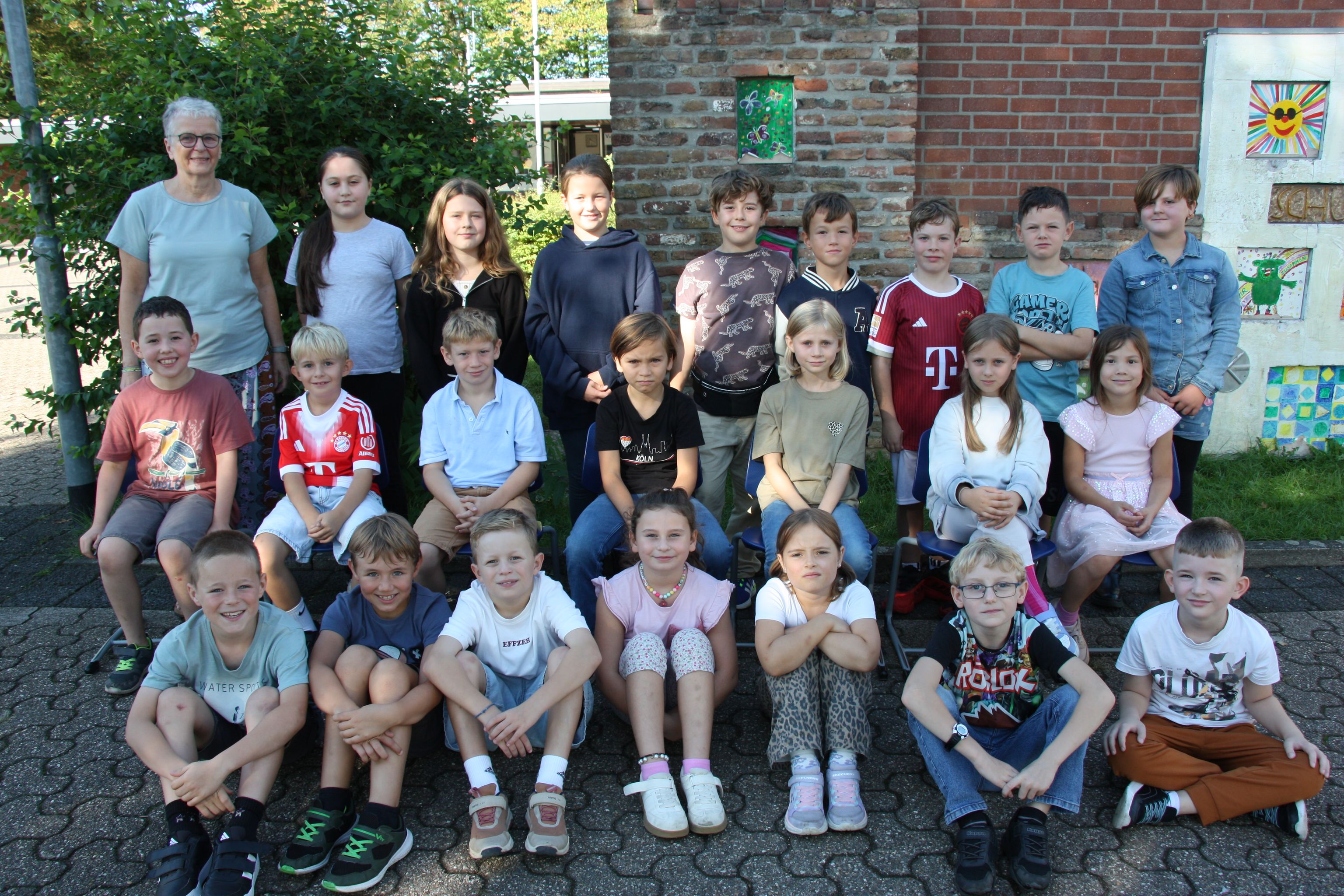 Großgruppe mit Kindern und Betreuern vor einem Haus im Freien.