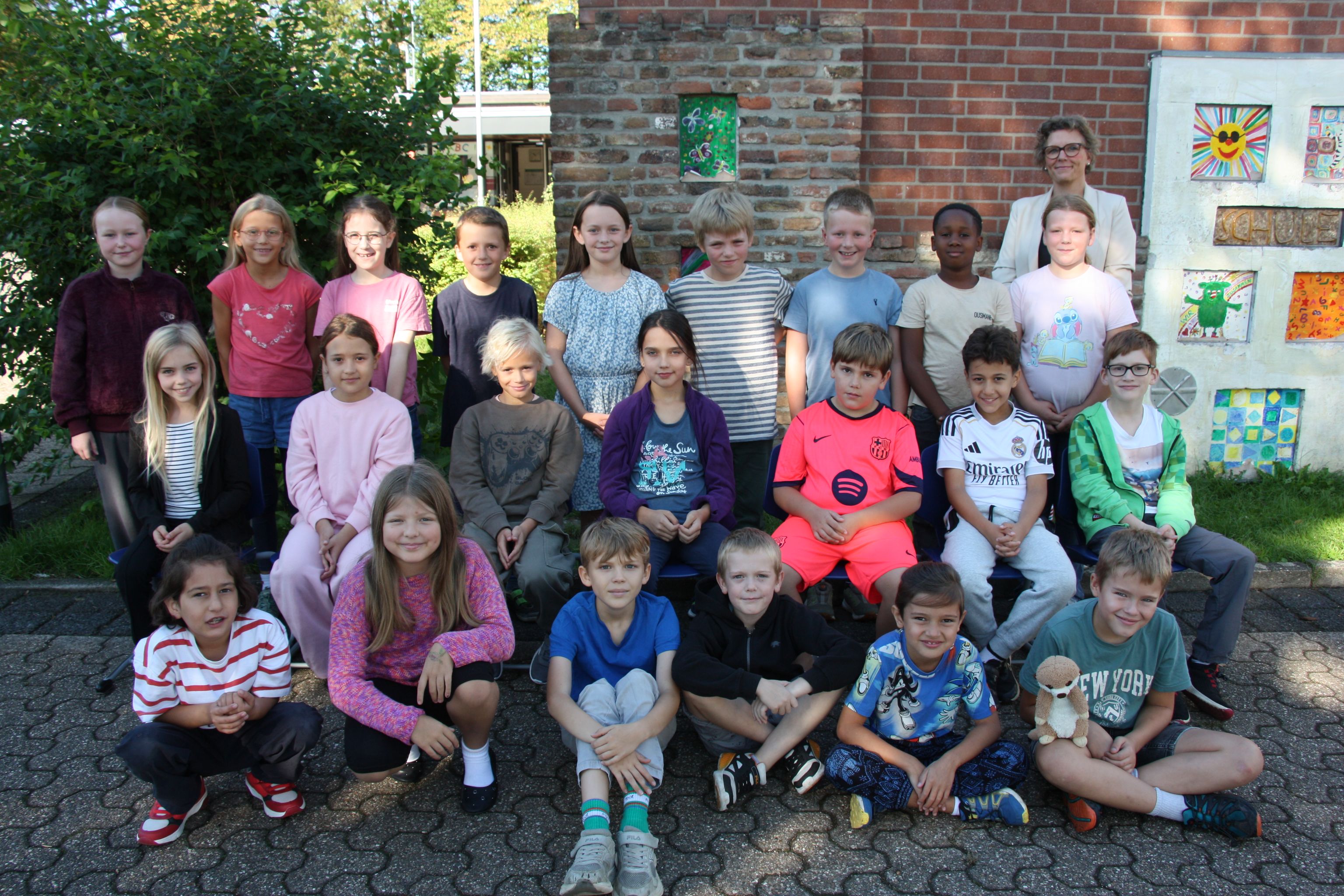 Große Gruppe Kinder und Erwachsene posiert fröhlich vor einem Haus.