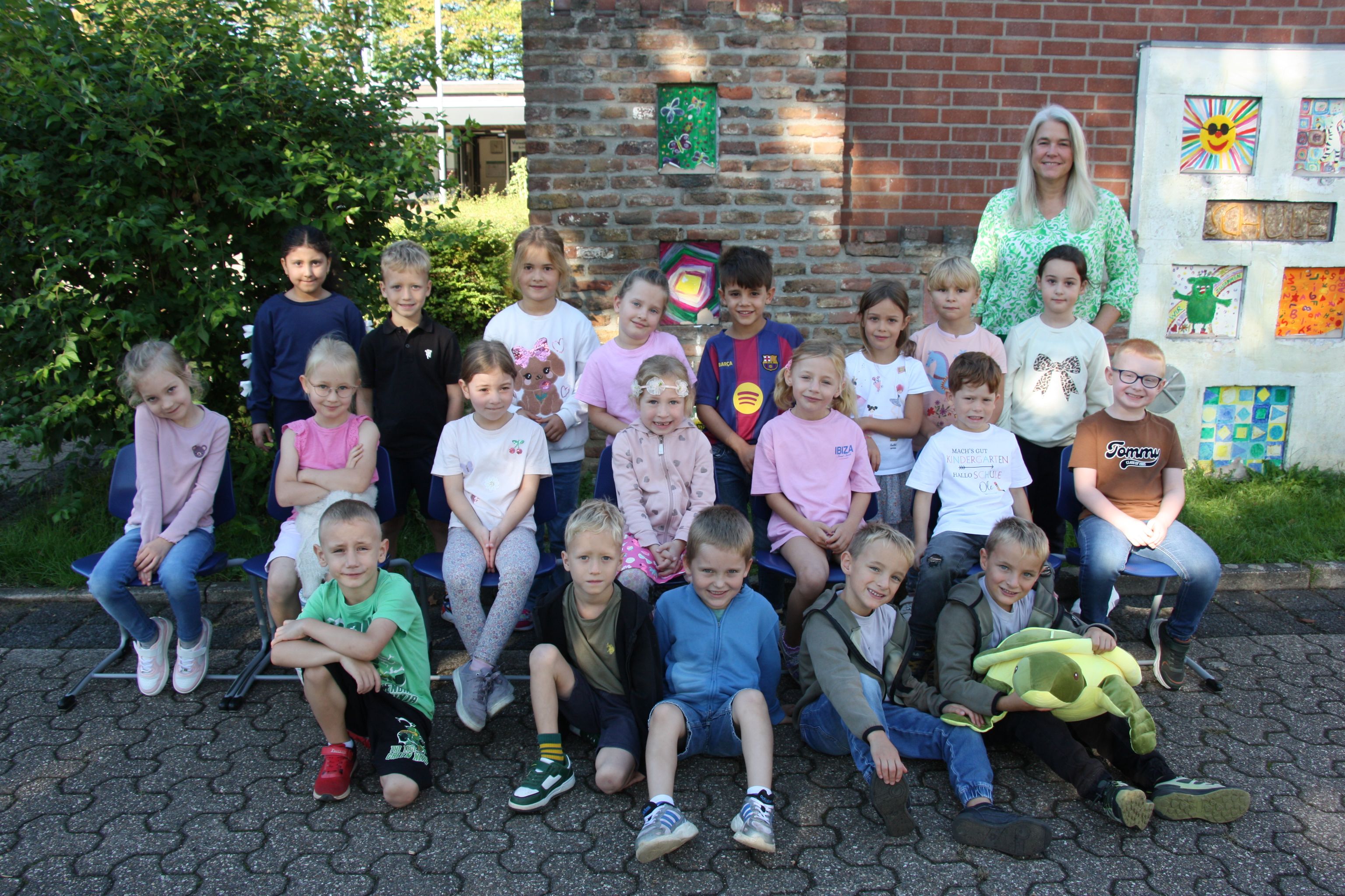 Gruppe fröhlicher Kinder und Betreuer vor einem Haus mit bunten Wandbildern.