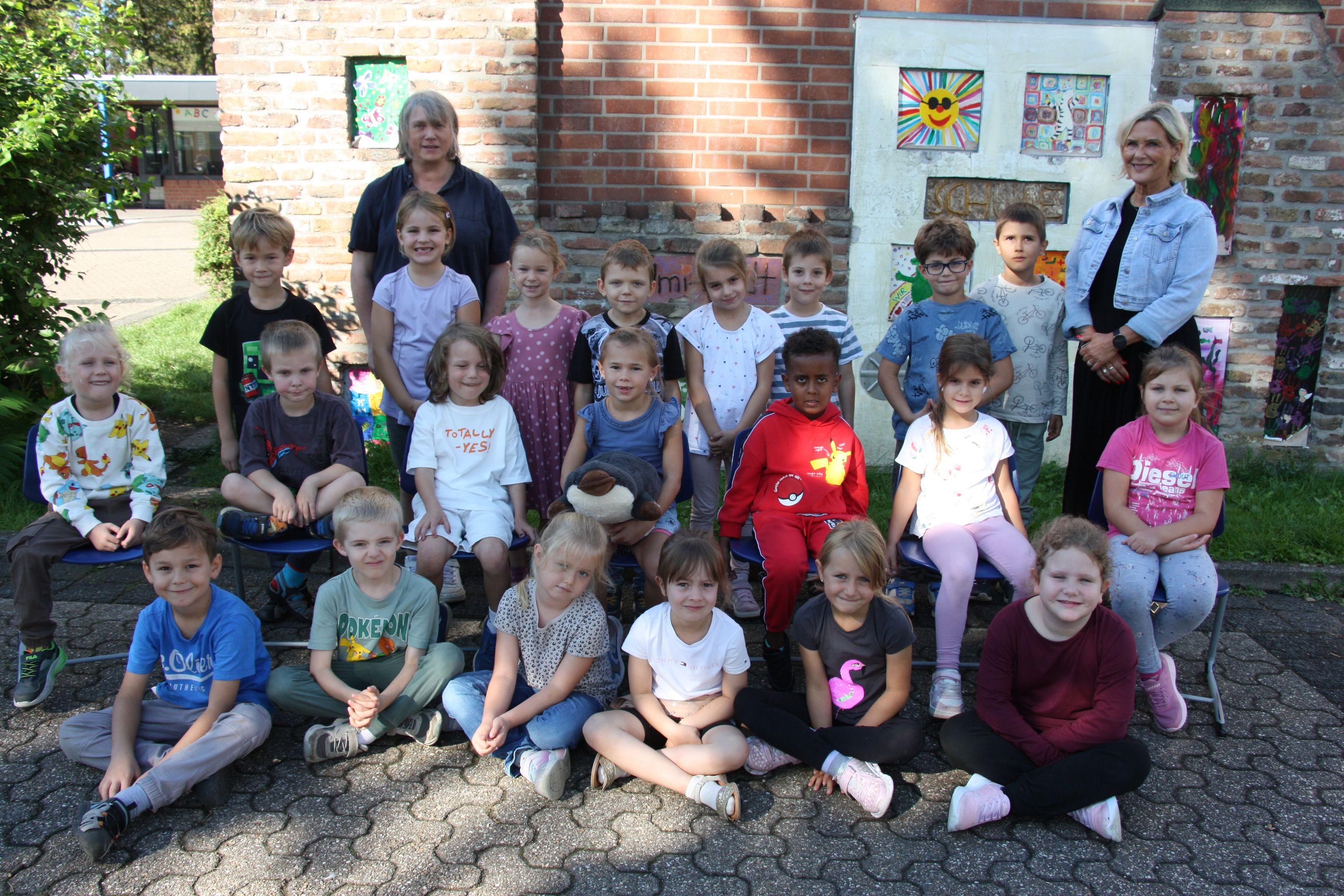 Gruppenfoto: Kinder und zwei Betreuer vor einem Kindergartengebäude.