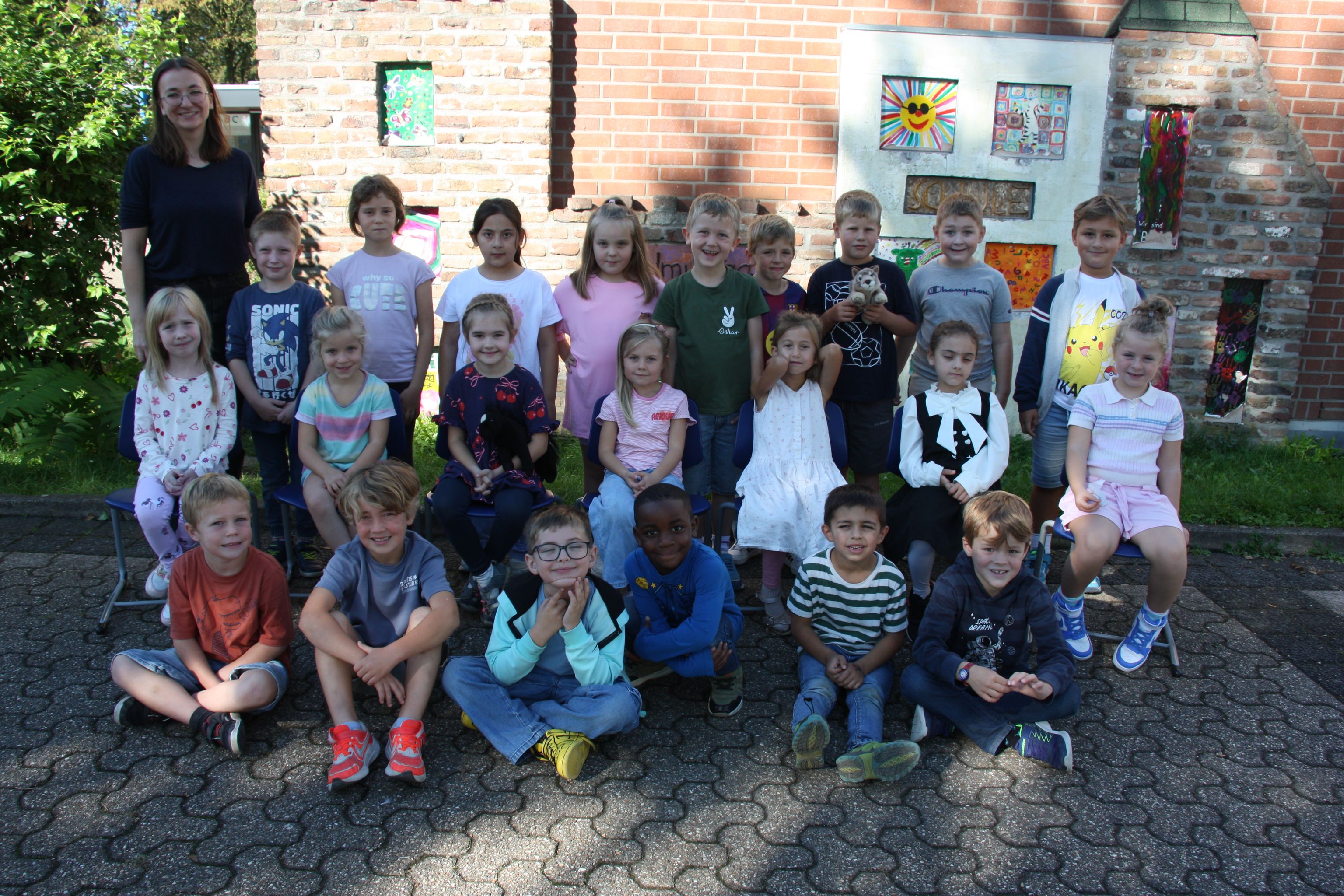 Gruppe glücklicher Kinder mit Betreuer vor einem Haus im Freien.