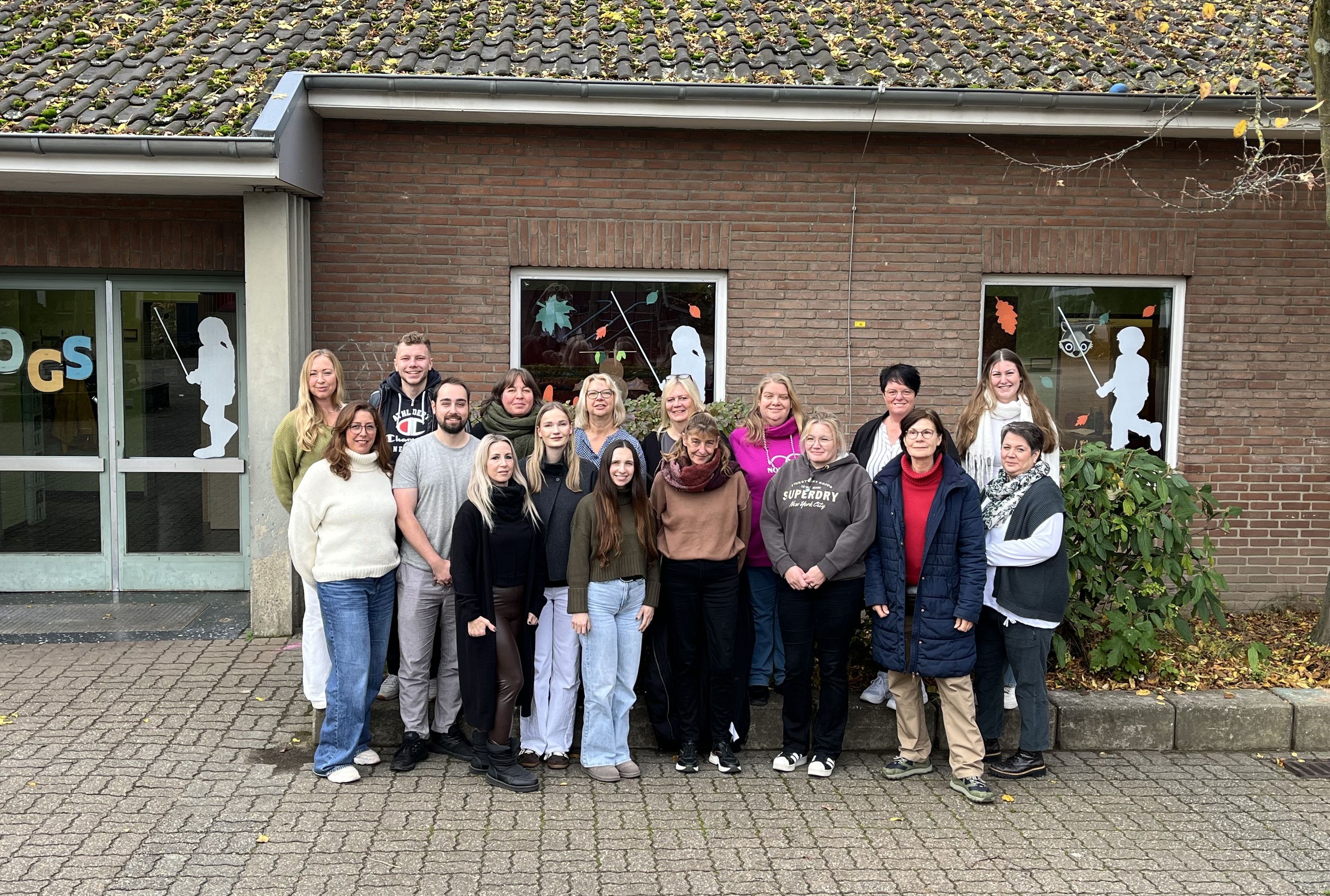 Gruppe von 16 Personen vor einem Gebäude mit Halloween-Deko posierend.