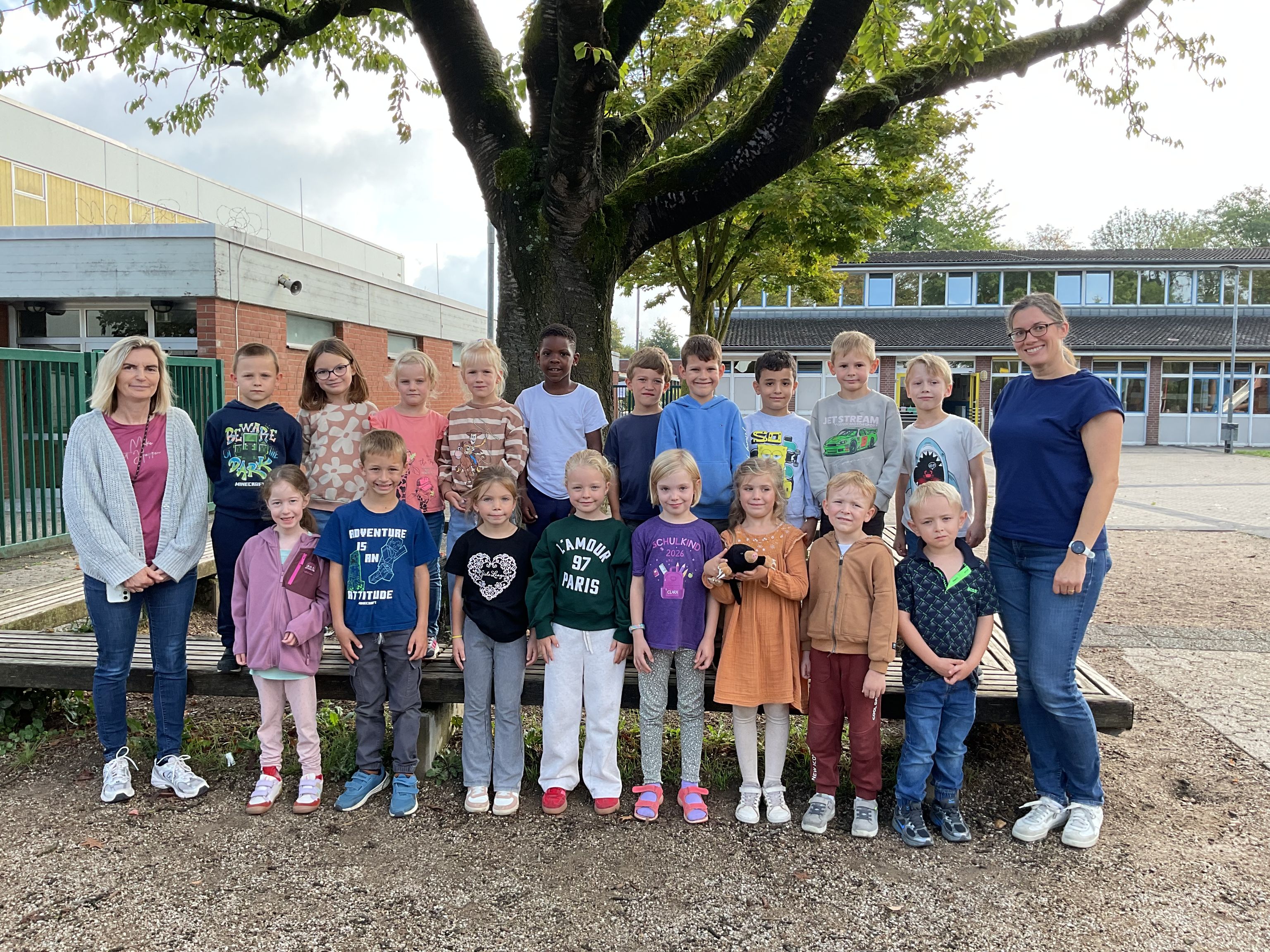 Gruppenfoto von Lehrkräften mit Grundschulkindern vor Schule.