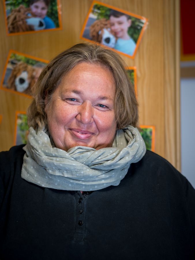 Lächelnde Person mit Schal vor Collage mit Tierfotos.